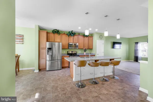 a kitchen with stainless steel appliances kitchen island granite countertop a refrigerator and a sink