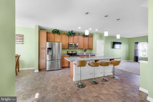 a kitchen with stainless steel appliances kitchen island granite countertop a refrigerator and a sink