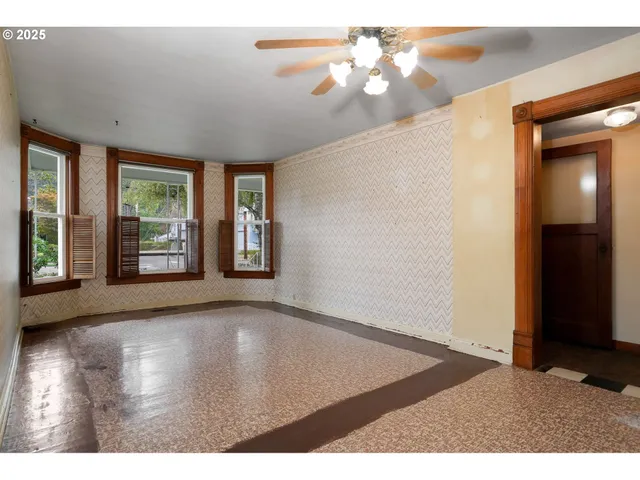 an empty room with windows and ceiling fan