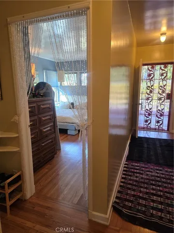 a walk in closet with wooden floor in front of a mirror
