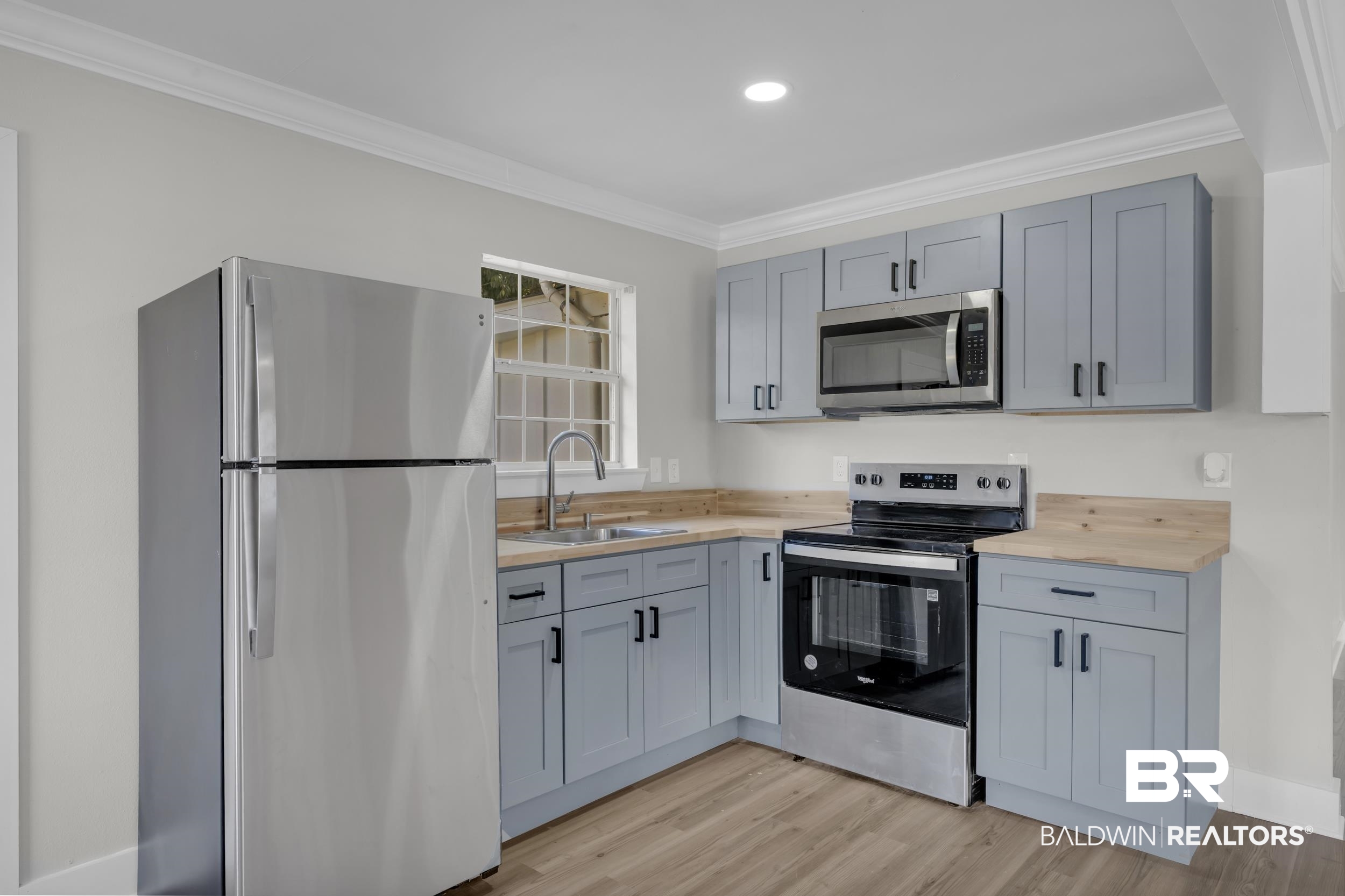 8351 Theodore Dawes Road Theodore, AL 36582 - Photo 35 of 46 Kitchen featuring stainless steel appliances, ornamental molding, light wood finished floors, gray cabinets, and butcher block counters