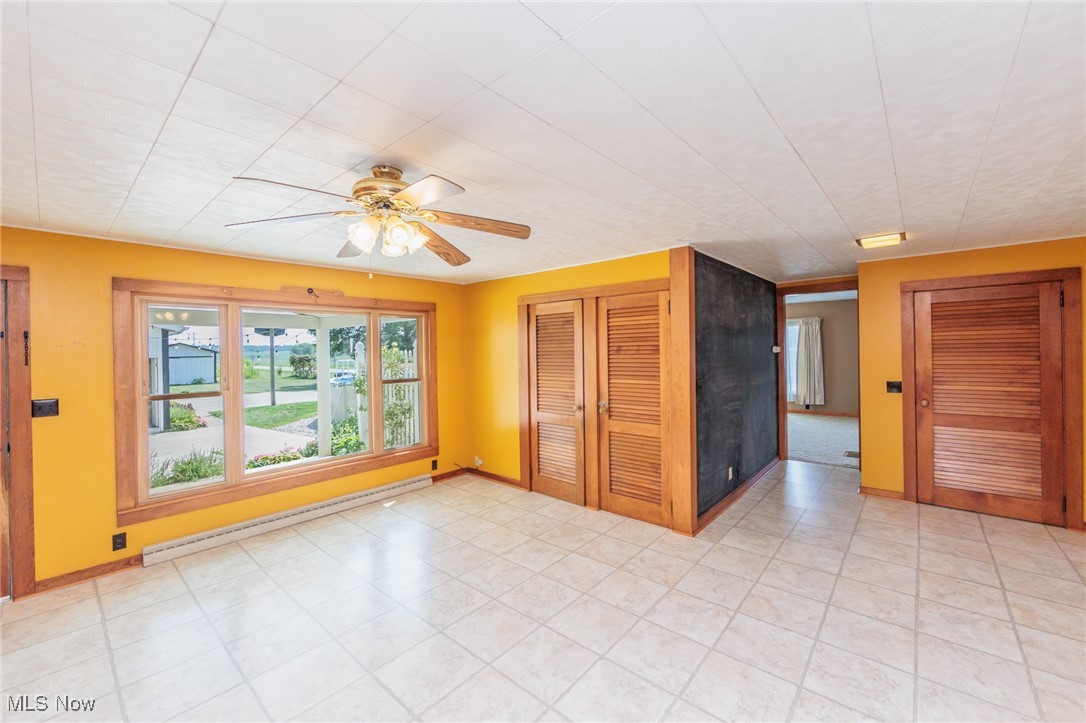 Spare room featuring a baseboard heating unit, light tile patterned flooring, and ceiling fan