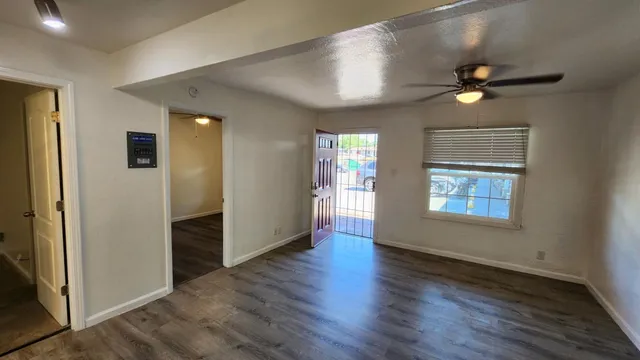an empty room with wooden floor cabinet and windows