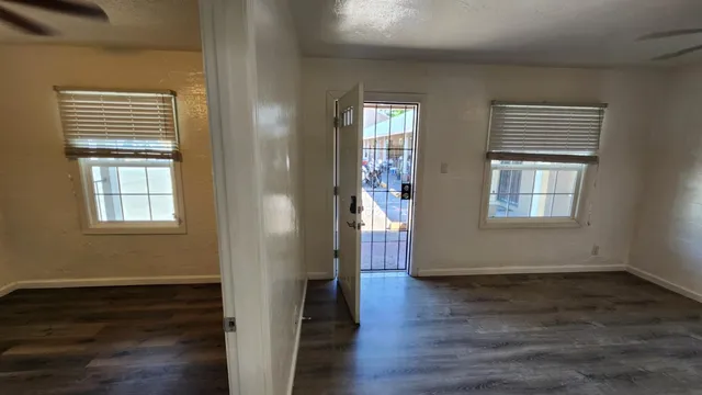 a view of an empty room with wooden floor and a window