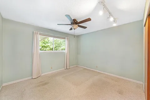 an empty room with a window and a fan