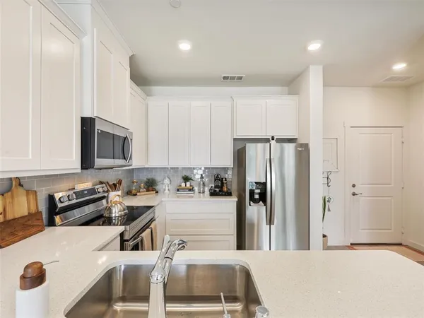 a kitchen with stainless steel appliances granite countertop a refrigerator sink and white cabinets