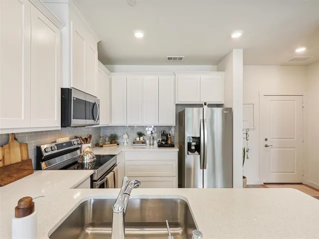 a kitchen with stainless steel appliances granite countertop a refrigerator sink and white cabinets