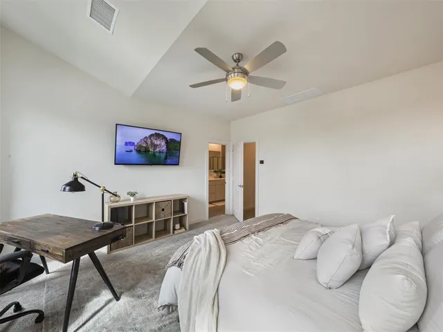 a bedroom with a bed a dresser and a chandelier