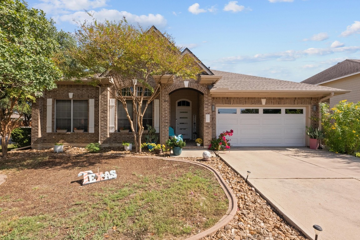 Traditional home featuring concrete driveway, brick siding, an attached garage, and a shingled roof