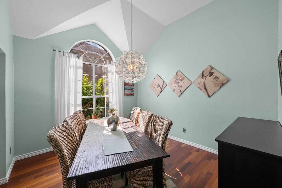 12201 Barrel Bend Austin, TX 78748 - Photo 13 of 35 Dining space featuring vaulted ceiling, a chandelier, and dark wood-style flooring