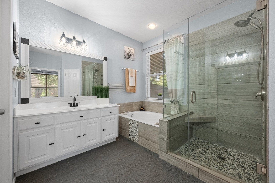 12201 Barrel Bend Austin, TX 78748 - Photo 18 of 35 Full bath with a garden tub, vanity, a stall shower, and dark tile patterned flooring
