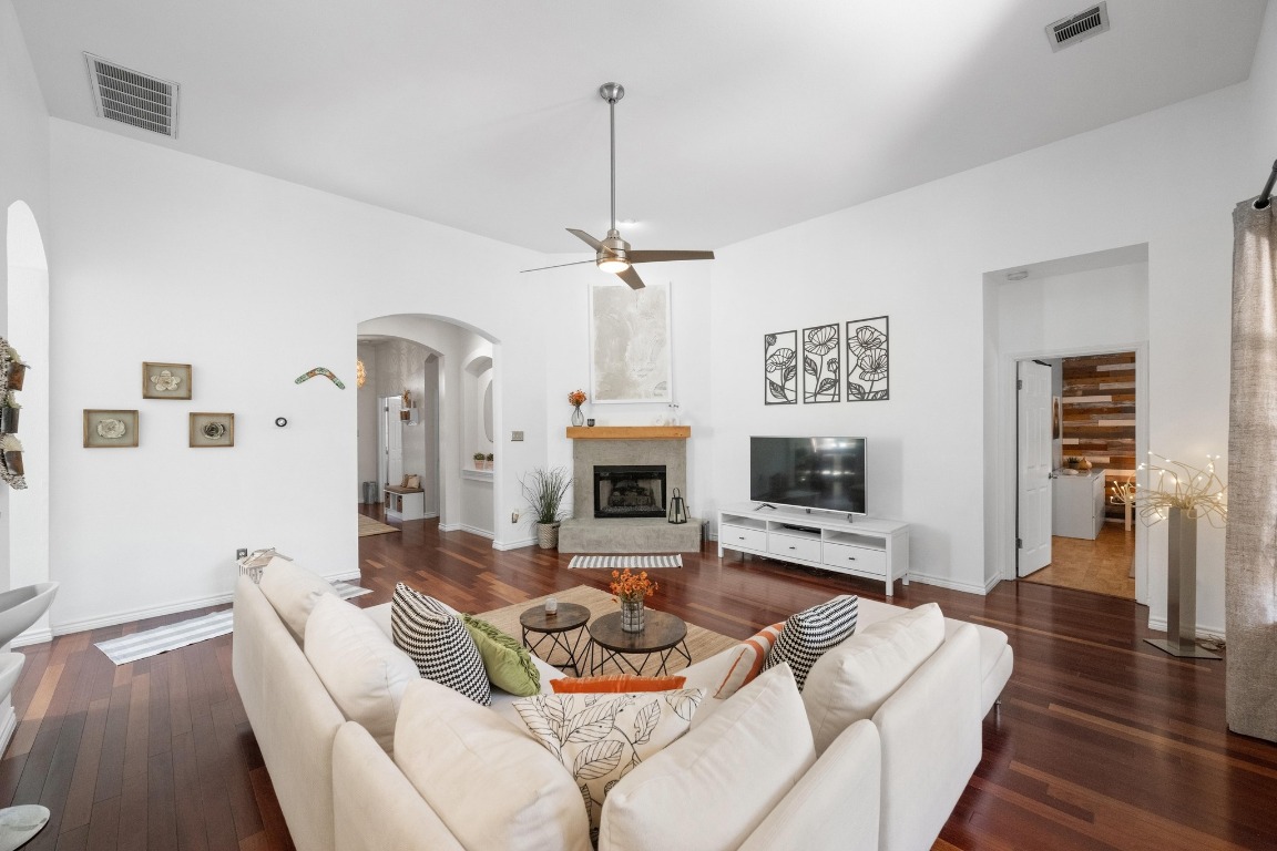 12201 Barrel Bend Austin, TX 78748 - Photo 6 of 35 Living room with arched walkways, dark wood finished floors, a glass covered fireplace, and a ceiling fan