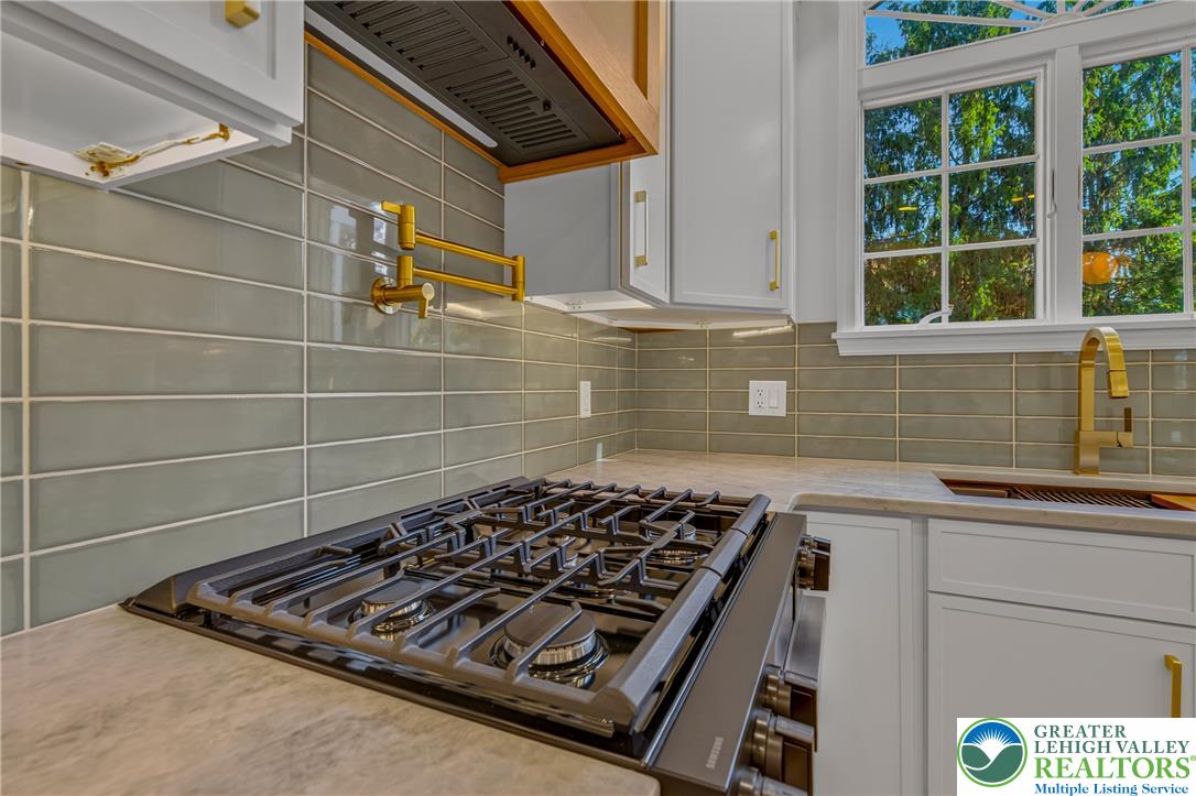 3130 Muirfield Road Center Valley, PA 18034 - Photo 24 of 63 Gleaming tile backsplashes and stone countertops frame a high-end gas range with brass fixtures.