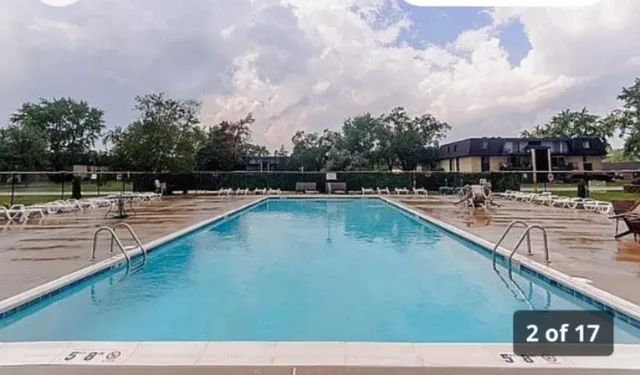 a view of swimming pool with outdoor seating and trees in the background