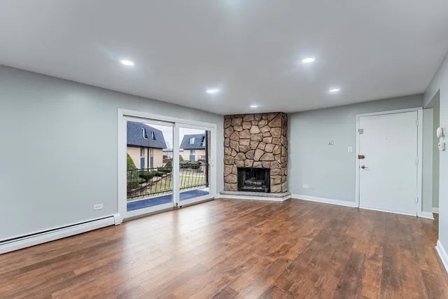 an empty room with wooden floor fireplace and windows