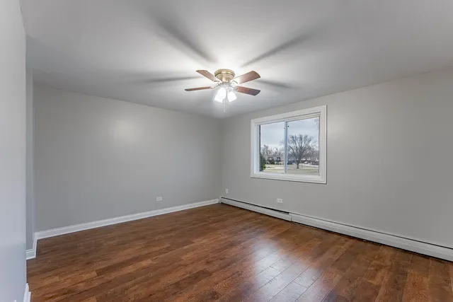 a view of an empty room with window and wooden floor