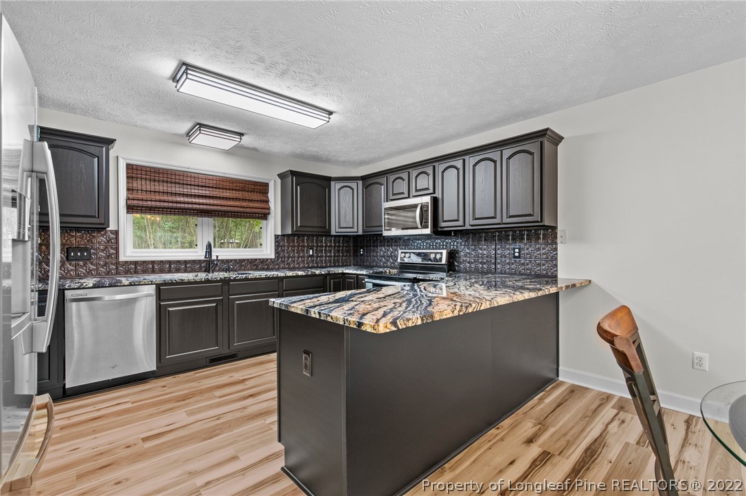30420 East Lake Road Wagram, NC 28396 - Photo 24 of 35 a kitchen with stainless steel appliances granite countertop a sink stove and refrigerator