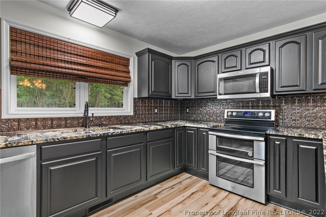 30420 East Lake Road Wagram, NC 28396 - Photo 25 of 35 a kitchen with stainless steel appliances granite countertop a sink stove microwave and cabinets