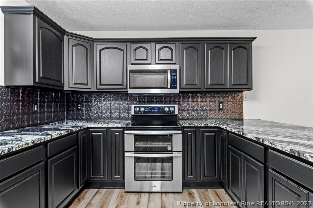 30420 East Lake Road Wagram, NC 28396 - Photo 26 of 35 a kitchen with granite countertop a stove sink and cabinets