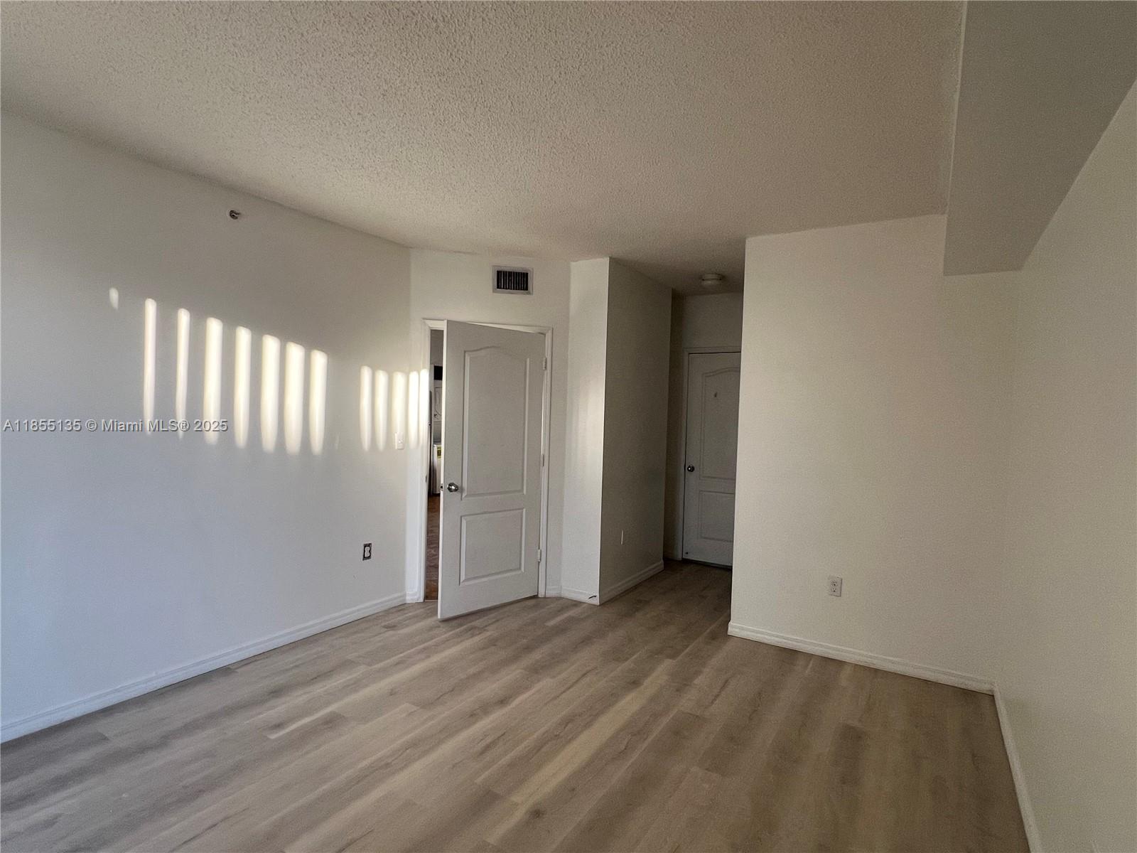 5077 Northwest 7th Street, Unit PH4 Miami, FL 33126 - Photo 24 of 25 a view of an empty room with wooden floor and a window