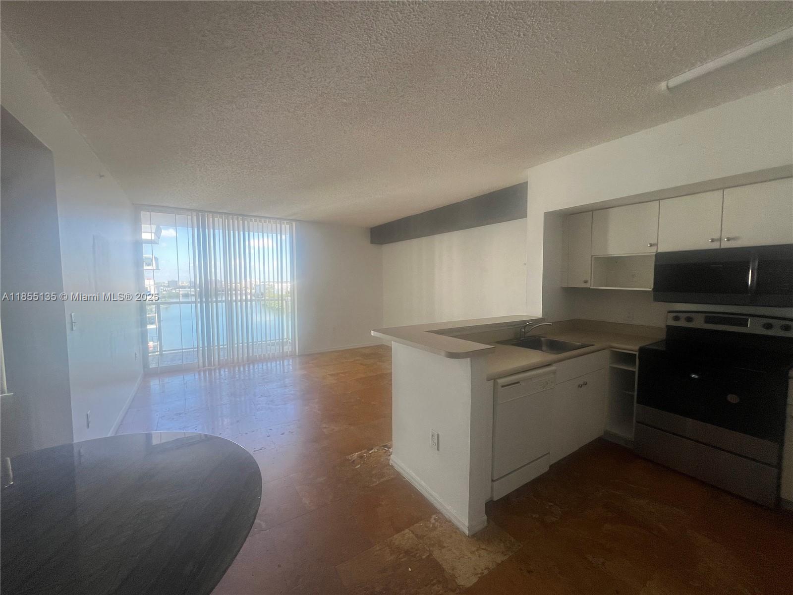 5077 Northwest 7th Street, Unit PH4 Miami, FL 33126 - Photo 7 of 25 a kitchen with granite countertop a sink and a stove top oven