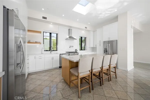 a kitchen with stainless steel appliances granite countertop a dining table chairs refrigerator and sink