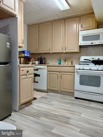 a kitchen with a stove white cabinets and white appliances