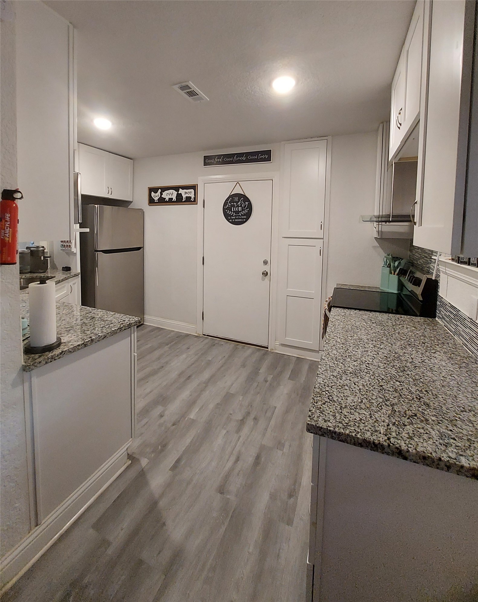 20202 McShepherd Road Georgetown, TX 78626 - Photo 18 of 40 Kitchen featuring white cabinets, light stone countertops, light wood-style flooring, stainless steel appliances, and recessed lighting