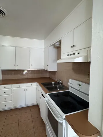 a kitchen with granite countertop a stove sink and cabinets