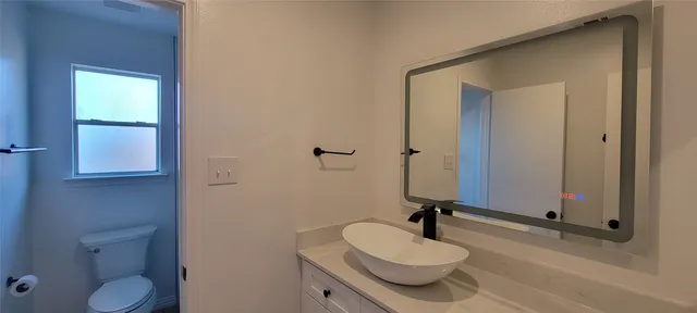a bathroom with a granite countertop sink toilet a mirror and shower