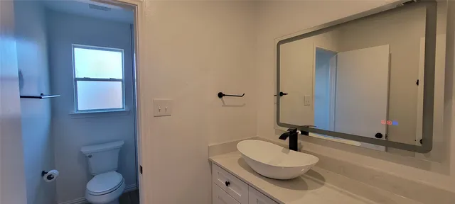 a bathroom with a granite countertop sink toilet and a mirror