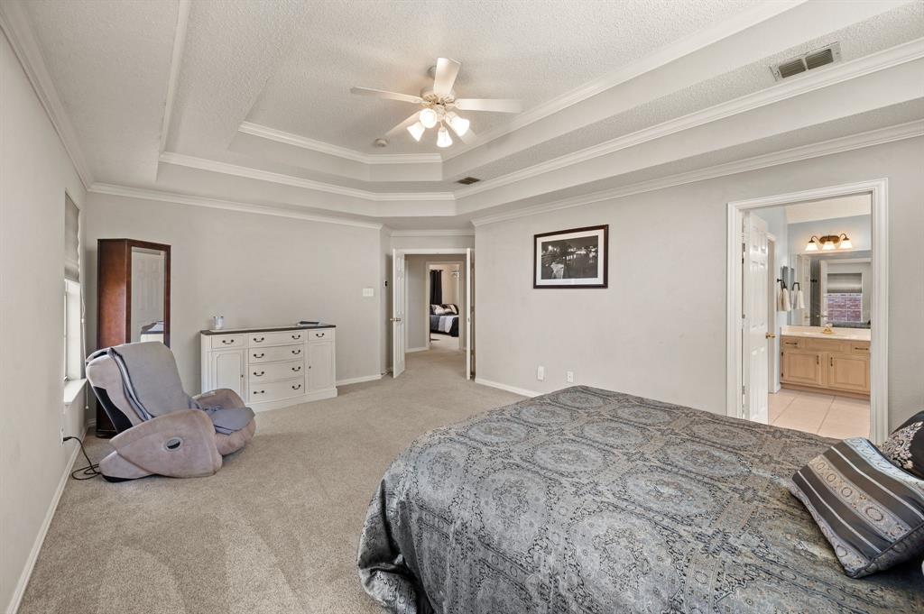 417 Shade Tree Circle Hurst, TX 76054 - Photo 22 of 39 a bedroom with a large bed and a chandelier