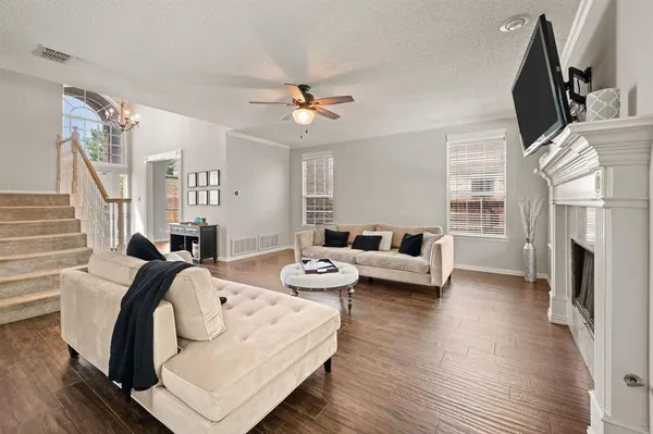 a open kitchen with stainless steel appliances granite countertop a stove top oven a sink dishwasher white cabinets and couches with wooden floor