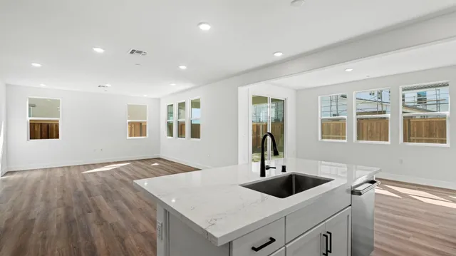 a view of a kitchen island a sink wooden floor and a living room