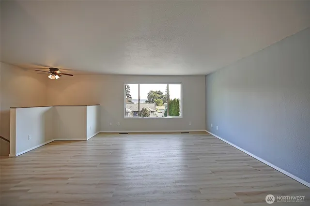 a view of a room with wooden floor and next to a window