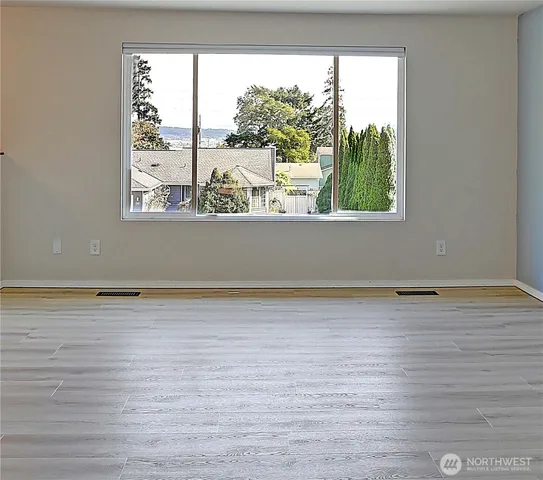 a view of empty room with wooden floor and window
