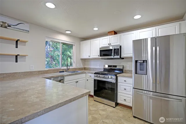 a kitchen with stainless steel appliances white cabinets and a stove top oven