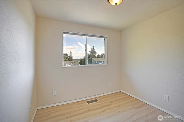 an empty room with a window and wooden floor