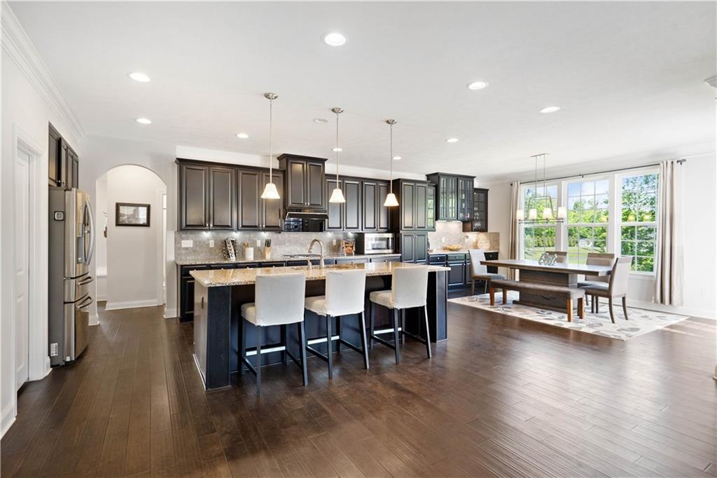 4449 Walnut Ridge Circle McDonald, PA 15057 - Photo 8 of 40 a open dining room with stainless steel appliances kitchen island granite countertop a stove a refrigerator a kitchen island a dining table and chairs with wooden floor
