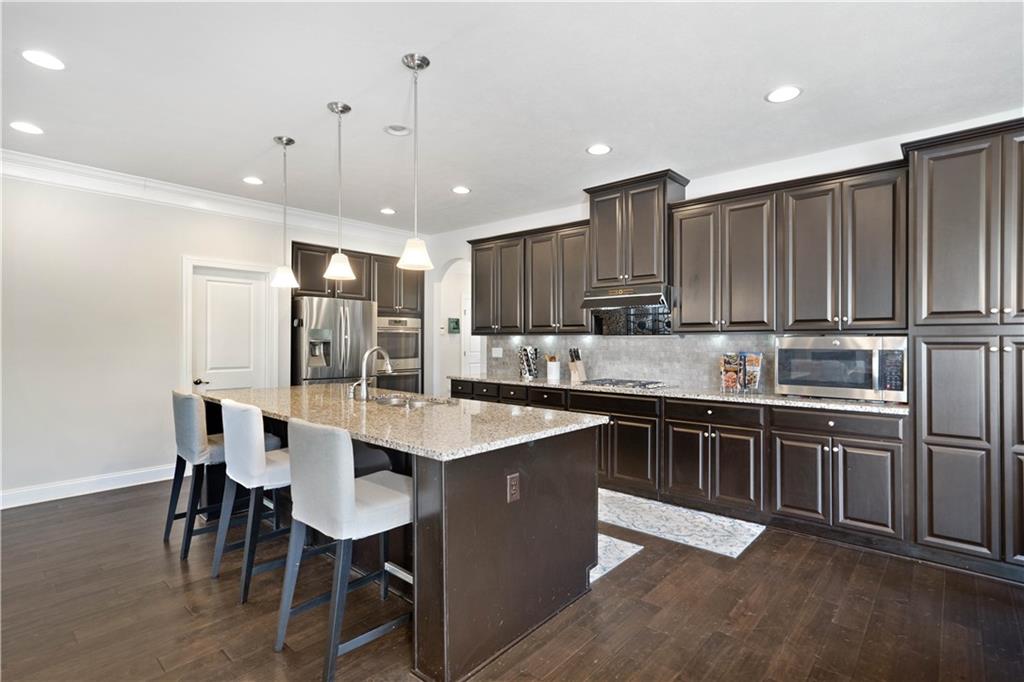 4449 Walnut Ridge Circle McDonald, PA 15057 - Photo 10 of 40 a kitchen with kitchen island granite countertop a sink a stove a refrigerator and island with wooden floor