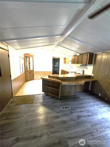 a kitchen with stainless steel appliances wooden floor and a view of living room