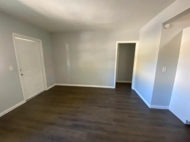a view of an empty room with wooden floor and a hallway