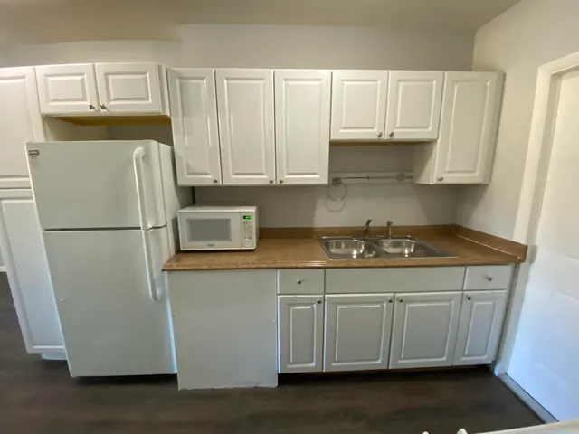 a kitchen with stainless steel appliances granite countertop a refrigerator sink and white cabinets
