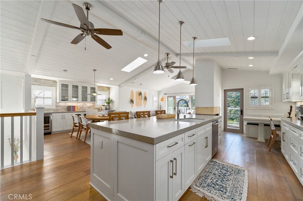 33 Cassis Dana Point, CA 92629 - Photo 8 of 49 a large kitchen with kitchen island a sink a center island a stove a chimney and a dining table with wooden floor
