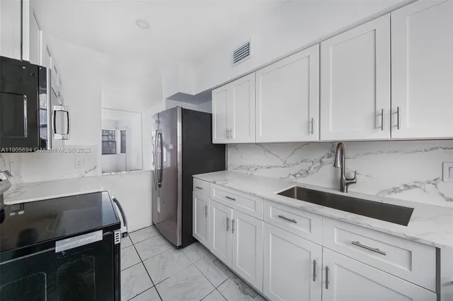 a kitchen with white cabinets and stainless steel appliances