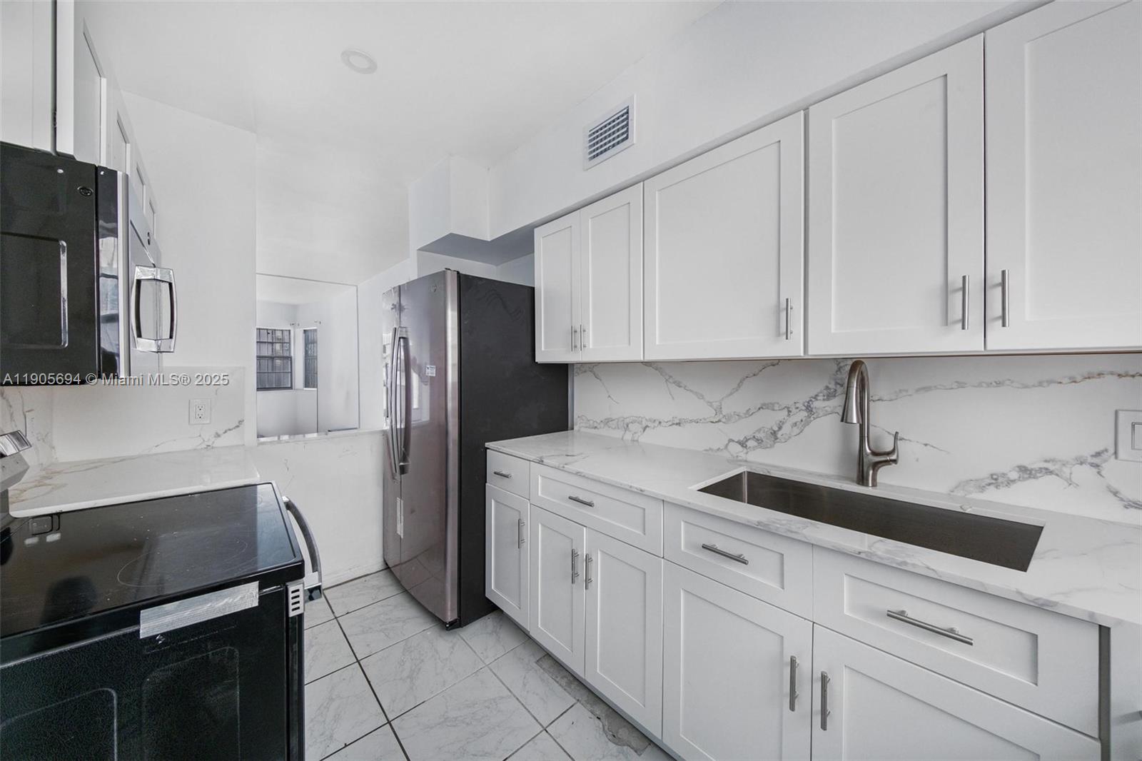 7712 Byron Avenue, Unit 2 Miami Beach, FL 33141 - Photo 11 of 24 a kitchen with white cabinets and stainless steel appliances
