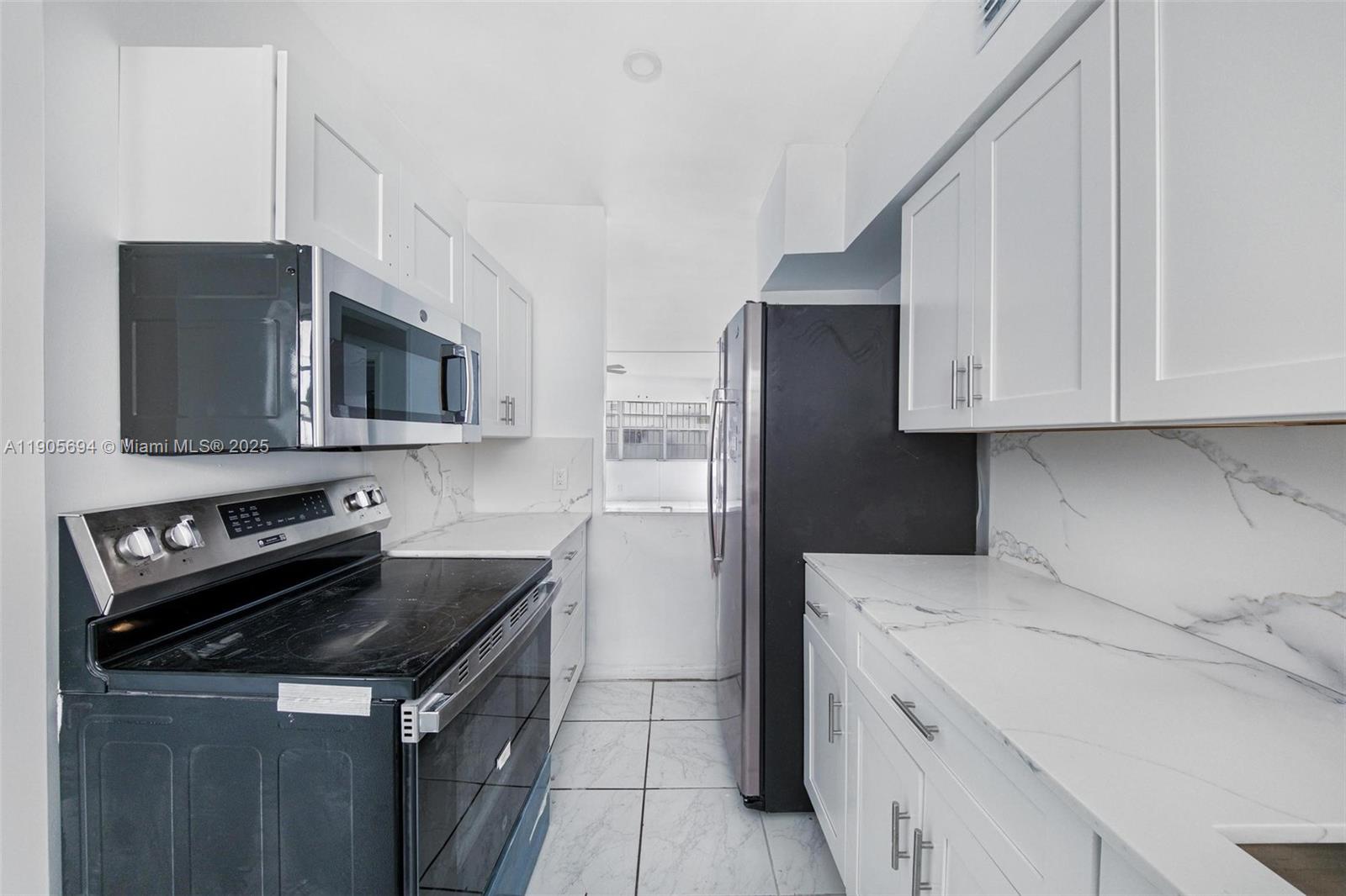 7712 Byron Avenue, Unit 2 Miami Beach, FL 33141 - Photo 12 of 24 a kitchen with a stove microwave and refrigerator