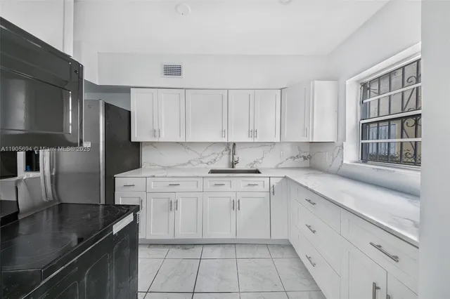 a kitchen with granite countertop white cabinets and stainless steel appliances