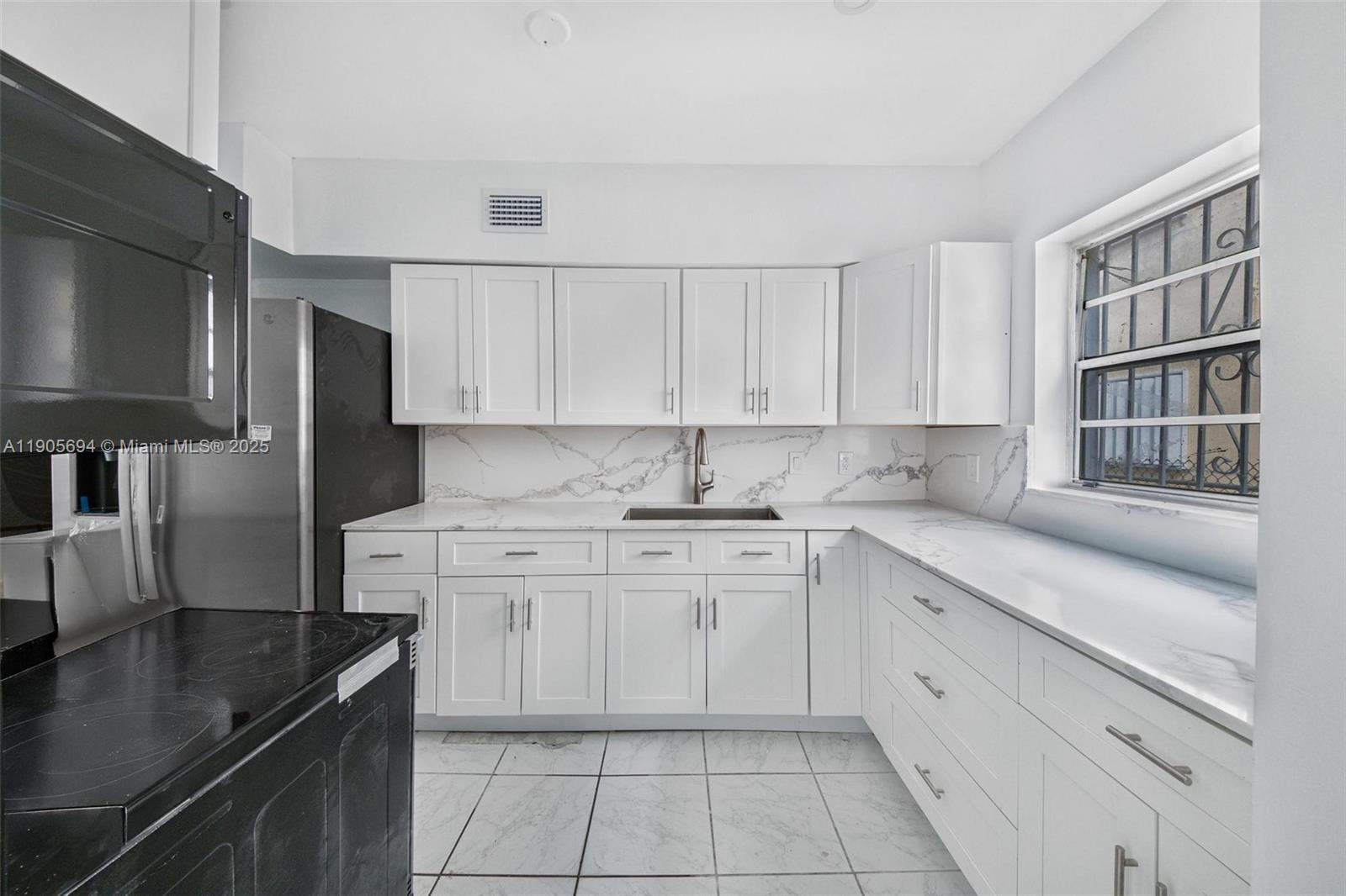 7712 Byron Avenue, Unit 2 Miami Beach, FL 33141 - Photo 10 of 24 a kitchen with granite countertop white cabinets and stainless steel appliances