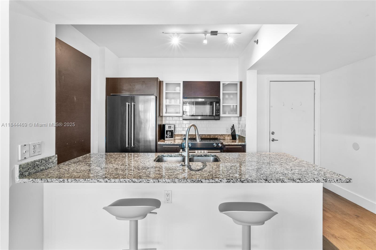 951 Brickell Avenue, Unit 1505 Miami, FL 33131 - Photo 11 of 48 a kitchen with kitchen island granite countertop a sink and a refrigerator